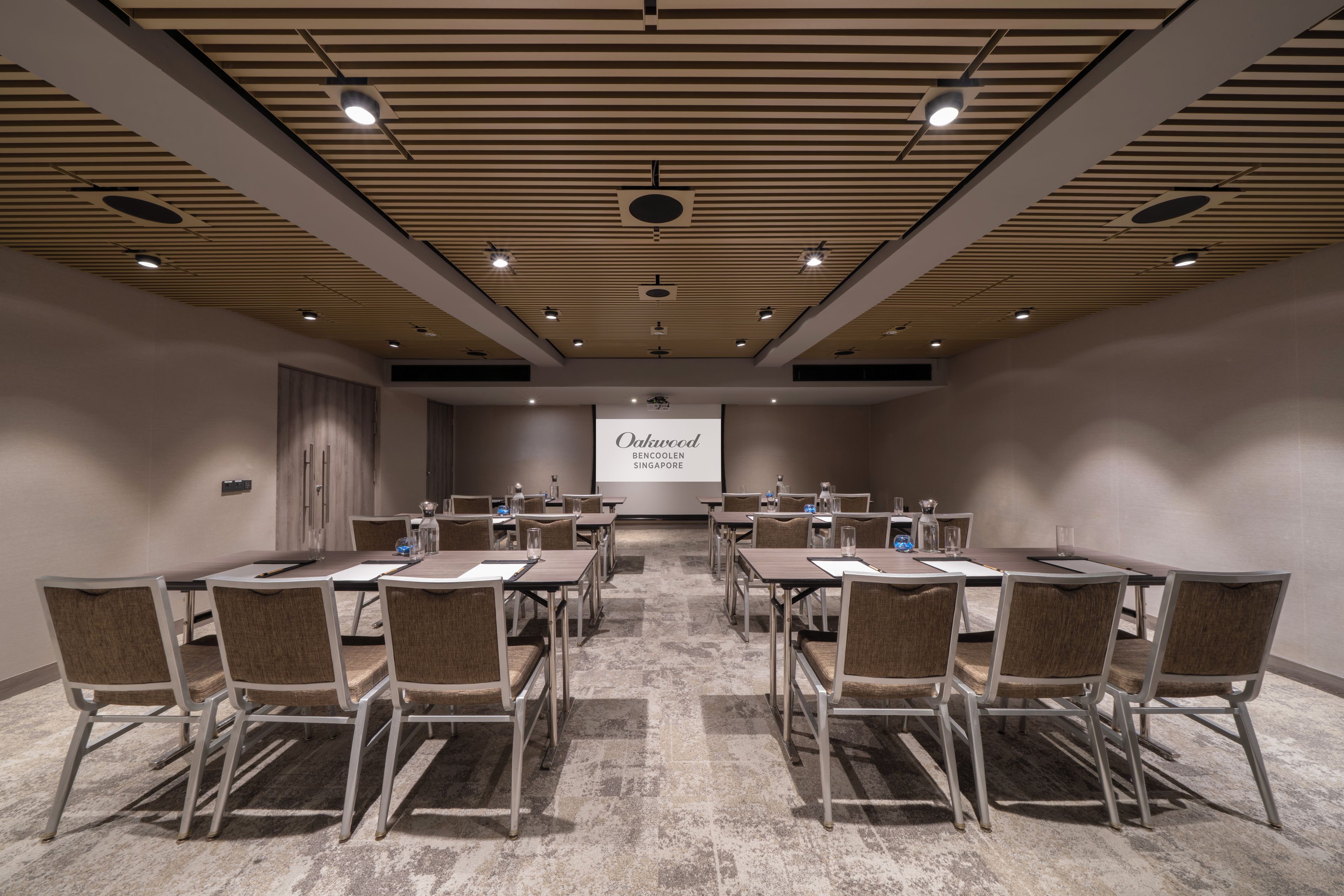 A conference room with a large screen displaying 'Oakwood Bencoolen Singapore'.