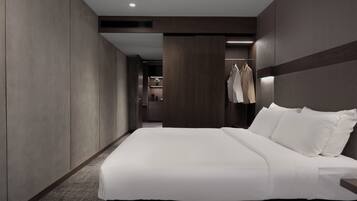 A modern hotel room with a large bed, a wardrobe, a mirror, and a clothing rack.