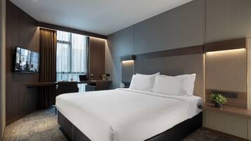Une chambre d’hôtel moderne dotée d’un grand lit, d’un bureau avec une chaise, d’un téléviseur à écran plat et d’une fenêtre avec des rideaux.