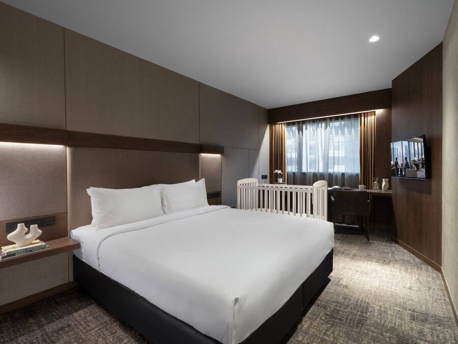 Una habitación de hotel con una cama grande, mesitas de noche, un escritorio y un televisor.