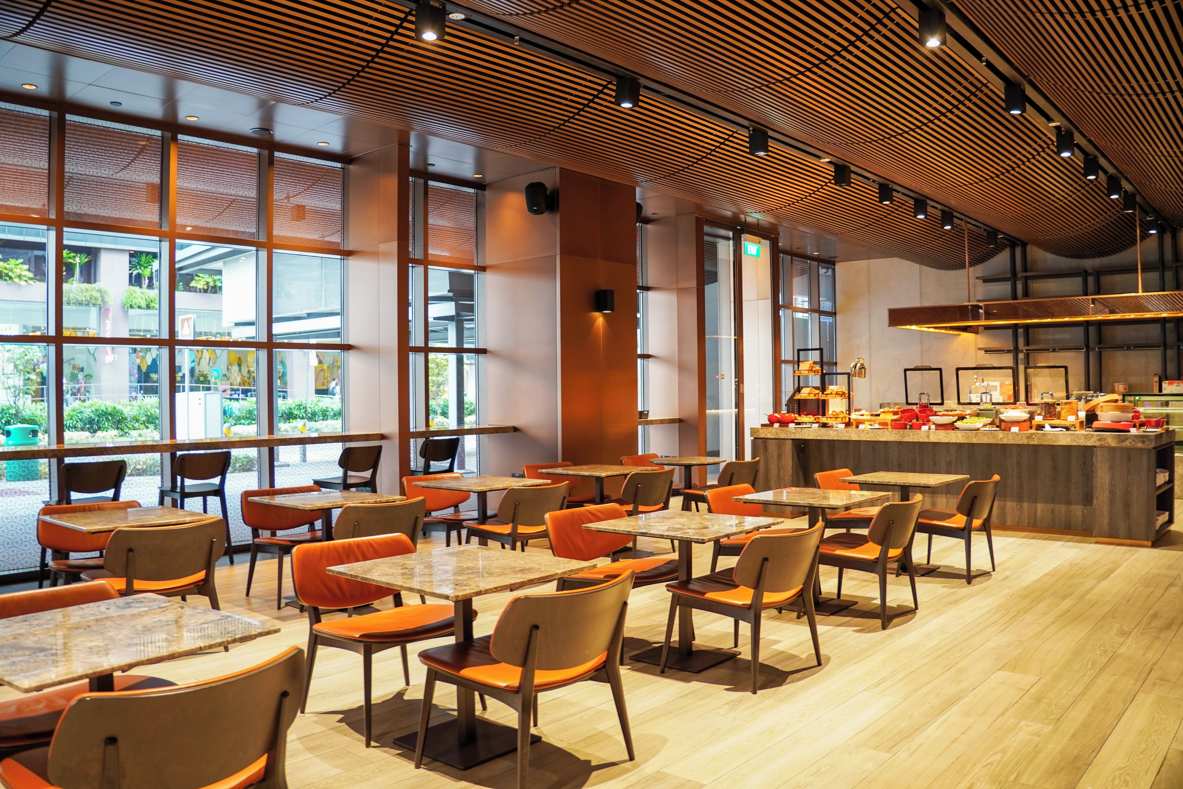 Un interior de restaurante moderno con múltiples mesas y sillas, ventanas amplias y una zona de bar central.