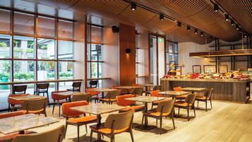 Un interior de restaurante moderno con múltiples mesas y sillas, ventanas amplias y una zona de bar central.