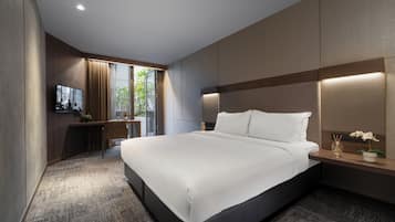Habitación de hotel moderna con una cama grande, un escritorio con televisor de pantalla plana y vistas a zonas verdes.