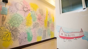 A hallway with a colorful floral mural and a drawing of a boat on the wall. - Happy Hi B&B (Taitung)