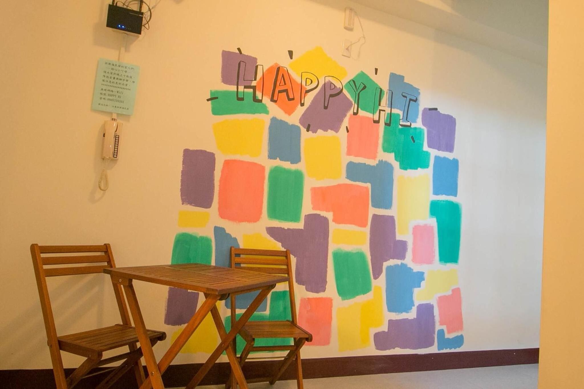 A room with a colorful abstract wall art, a wooden table, and two chairs.