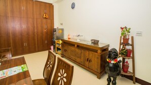 A dining area with wooden cabinets, a dining table, chairs, and a decorative black dog statue. - Happy Hi B&B (Taitung)