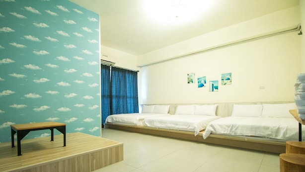 A room with a bed, a bench, and a wall with cloud patterns. - Happy Hi B&B (Taitung)