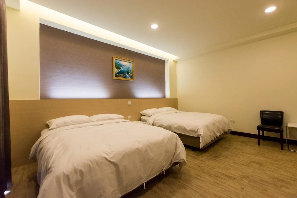 Une chambre d’hôtel avec deux lits simples, un plancher en bois, un tableau au mur et une chaise.