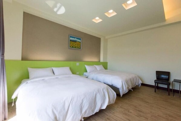 A hotel room with two beds, a green headboard, a small TV, and a painting on the wall. - Pandora Elevator B&B (Taitung)