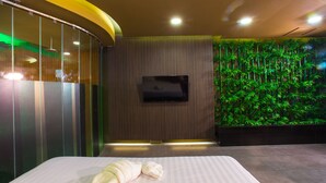 Una habitación de hotel con una cama, un televisor de pantalla plana en la pared y un jardín vertical.