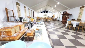 A dining area with checkered flooring, wooden tables, and chairs. There are baskets of bread and a toaster on the table. - Gyeongju Kids & Family Hotel (Gyeongju)