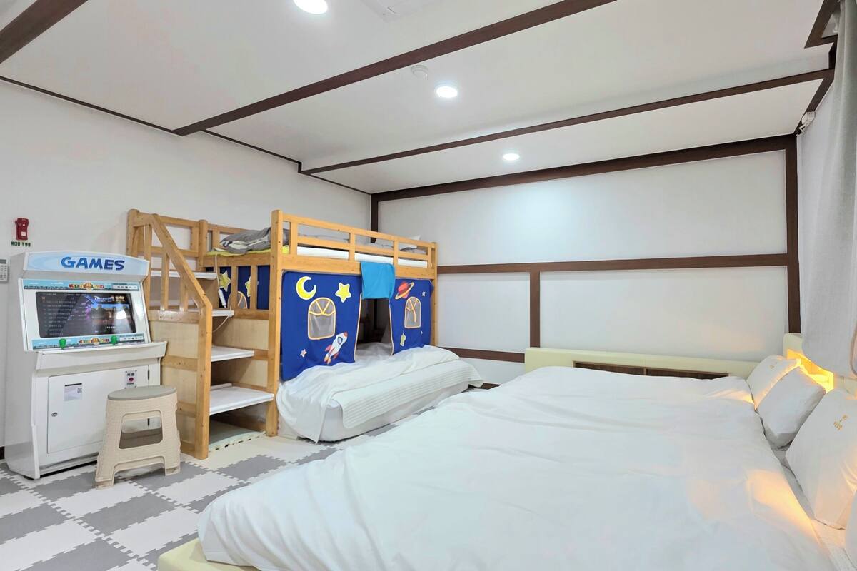 Habitación de hotel con literas, un escritorio pequeño con una computadora y una cama con almohadas.
