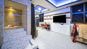 A modern bathroom with a shower, a bathtub, and a toilet. There is a TV mounted on the wall and a table with chairs in the room. - Gyeongju Kids & Family Hotel (Gyeongju)