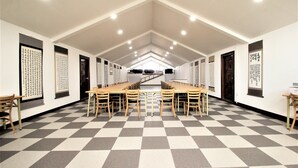 A conference room with a long table and chairs, white walls, and black-and-white checkered flooring. - Gyeongju Kids & Family Hotel (Gyeongju)