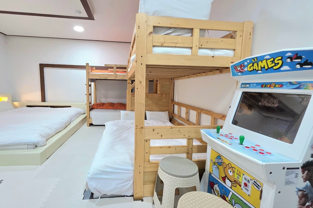 Una habitación con literas, una mesita, una silla y una consola de videojuegos para niños.