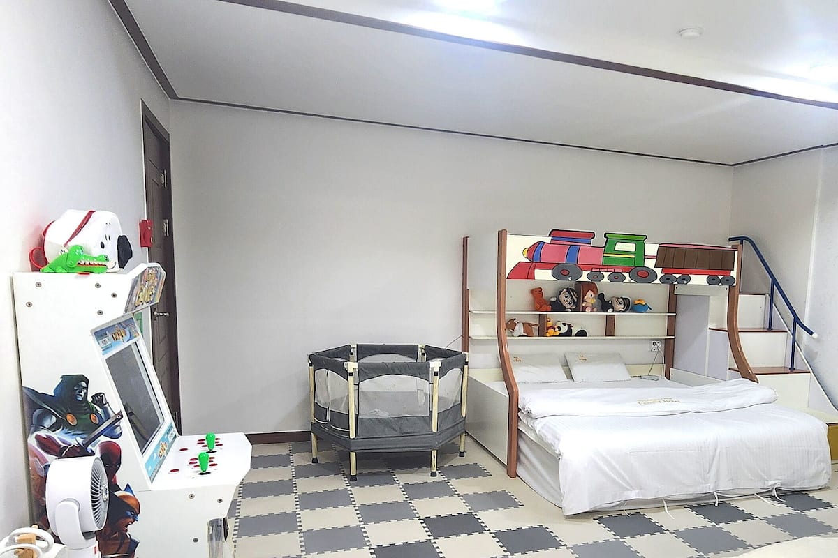 Habitación infantil con una cama litera, un escritorio con computadora y juguetes, y una televisión montada en la pared.