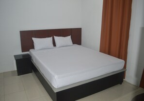 A standard hotel room with a single bed, a nightstand, and a plain wall. - Lovetel (Padang)