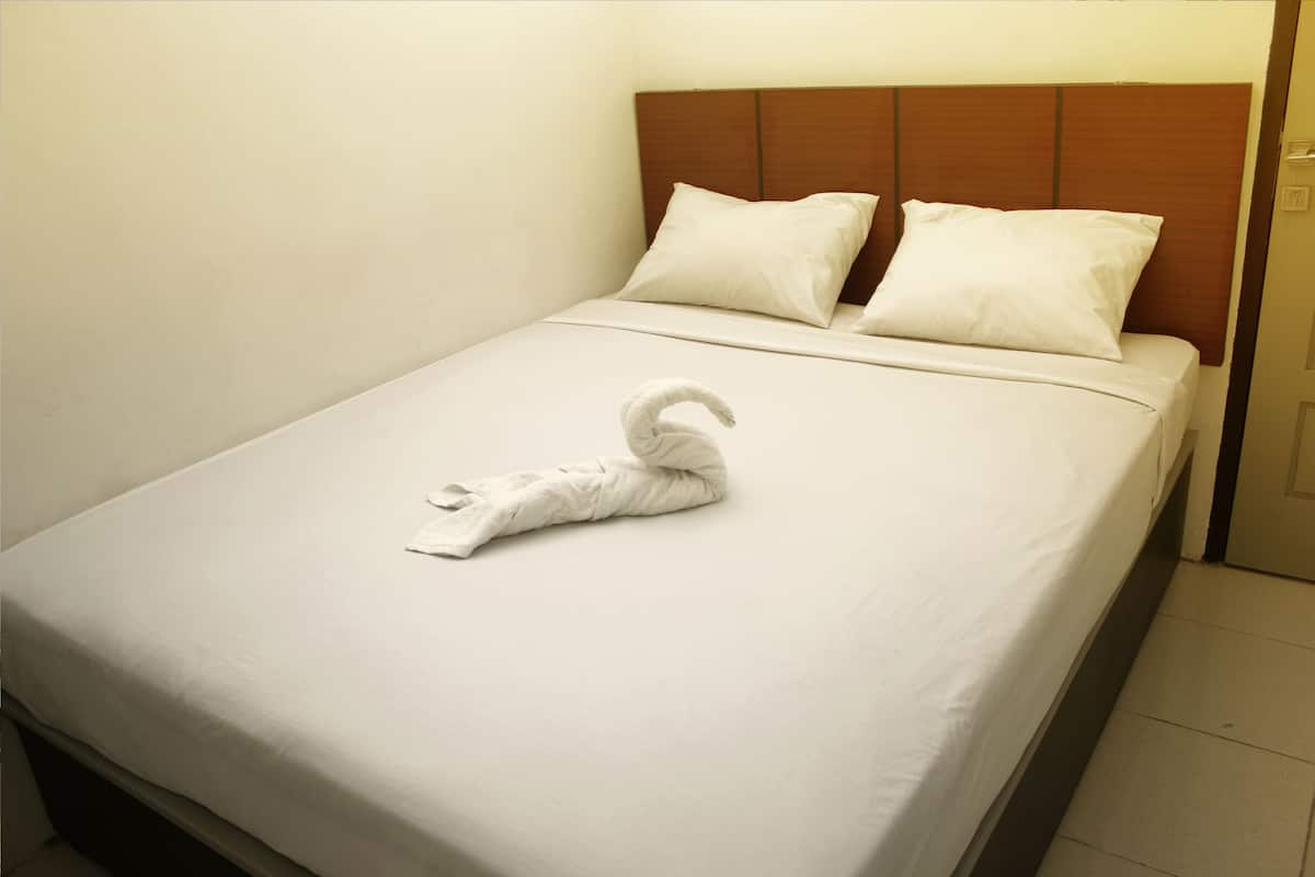 A neatly made bed with a folded towel and two pillows.