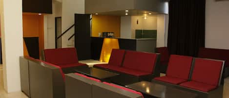 A modern living room with red and grey furniture, a staircase, and a kitchen area.