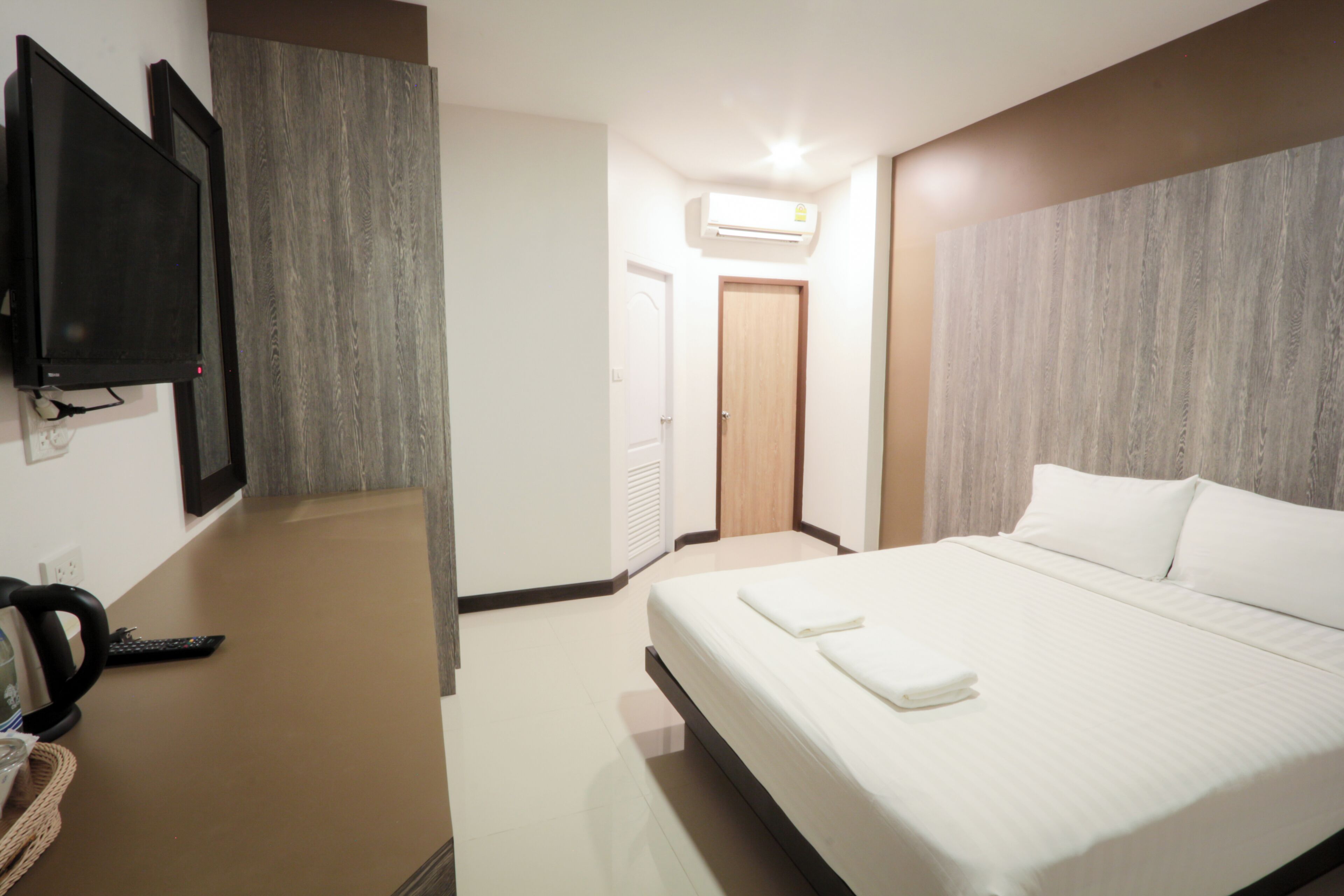 A hotel room with a bed, a TV, a coffee maker, and an air conditioning unit.