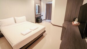 Quarto de hotel moderno com uma cama grande, televisão de tela plana e um pequeno espaço de estar.