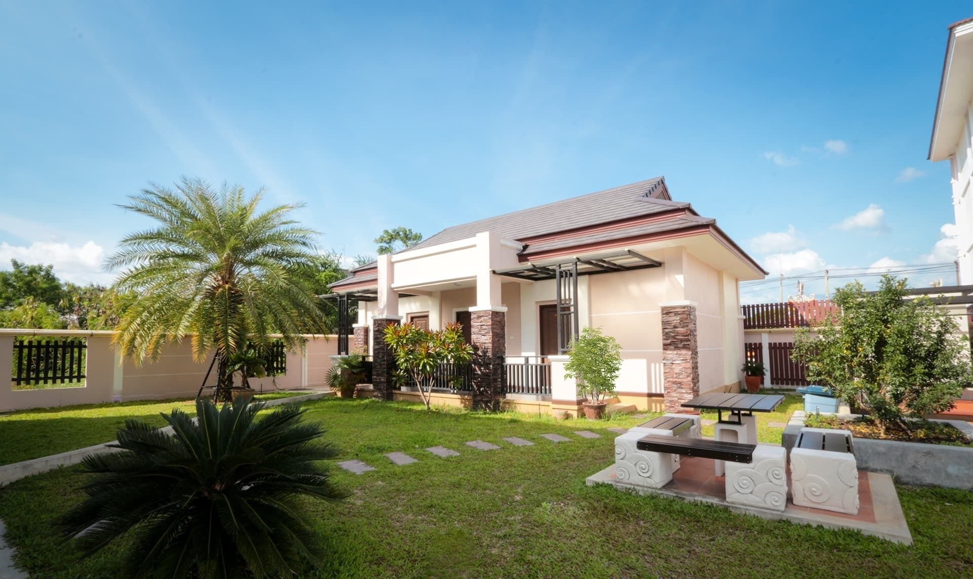 A modern two-story house with a covered patio, a well-maintained lawn, and a variety of potted plants.