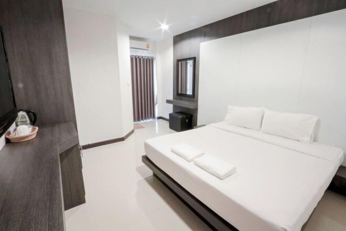 Een moderne hotelkamer met een groot bed, een flatscreen televisie, een donker houten paneel en een klein tafeltje met een mandje.