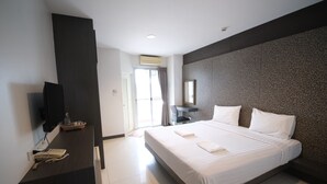 Una habitación de hotel moderna con una cama grande, un escritorio con teléfono, un televisor de pantalla plana y un ventanal amplio.