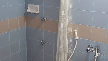 A bathroom with a toilet, a shower with a curtain, and a soap dispenser.