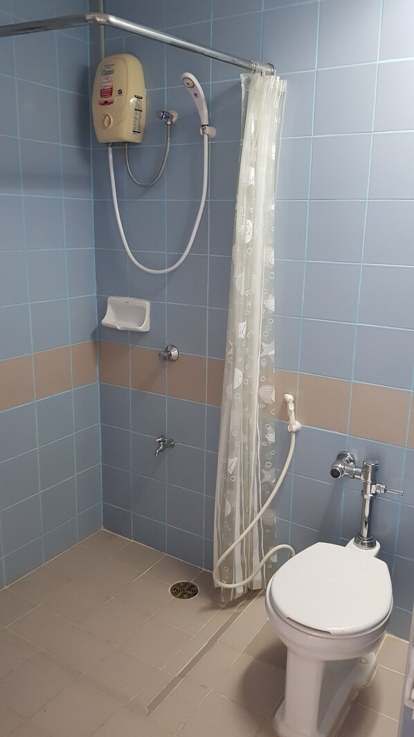 A bathroom with a toilet, a shower with a curtain, and a soap dispenser. - Aek Udon Apartment (Udon Thani)
