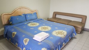 A bed with a blue and beige bedspread, two pillows, and a folded white towel. - Aek Udon Apartment (Udon Thani)