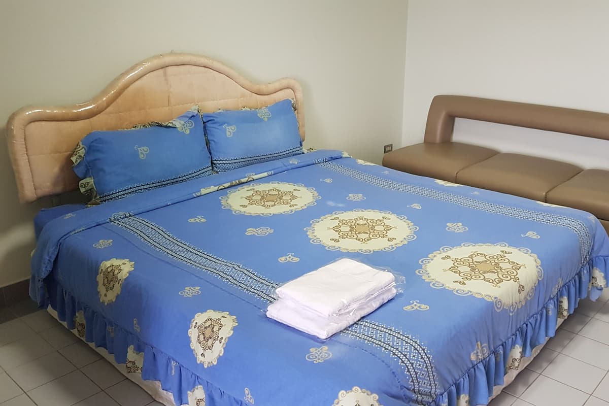 A bed with a blue and beige bedspread, two pillows, and a folded white towel.