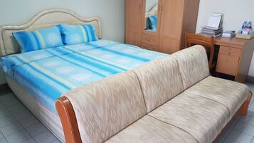 Un dormitorio con una cama, un armario de madera, un escritorio y una silla.