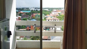A balcony with a view of a residential area, a metal railing, and a brown curtain. - Aek Udon Apartment (Udon Thani)
