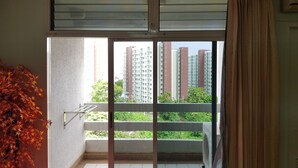 A balcony with a view of high-rise buildings and greenery. - Aek Udon Apartment (Udon Thani)