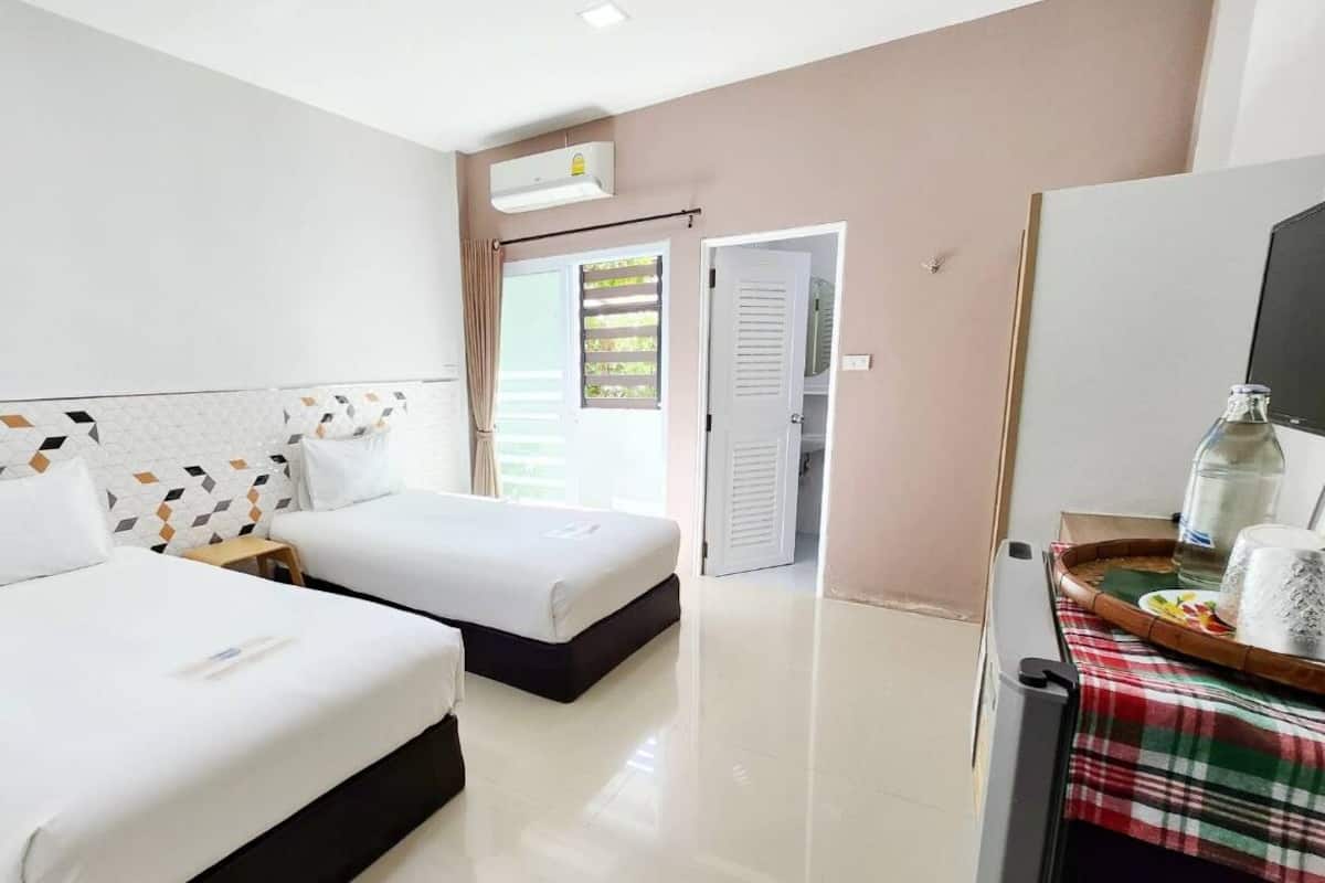 A hotel room with two beds, a bathroom, and a dining area with a table and chairs.