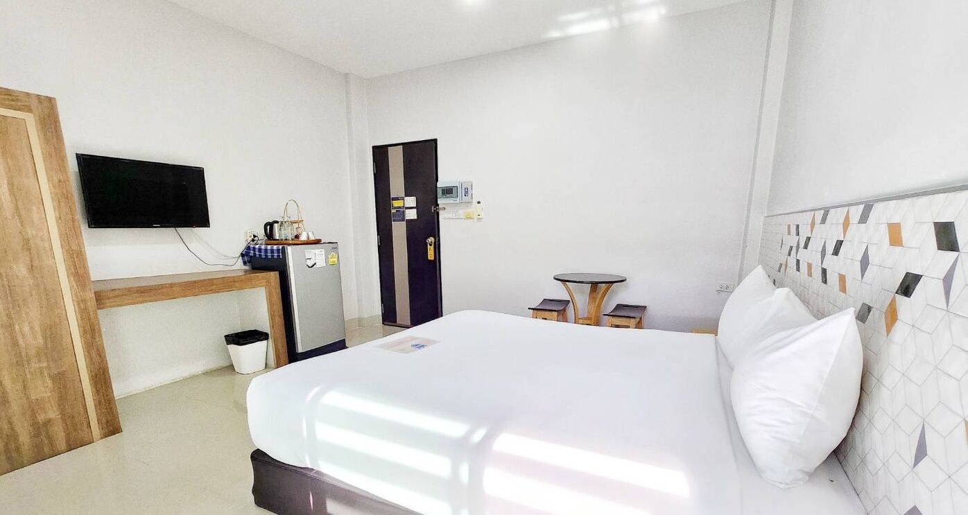 A hotel room with a bed, a desk with a chair, a television, a small table, and a microwave.