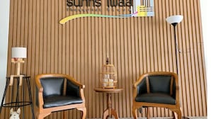 A wooden wall with a sign reading "suins iwaa thangphat place". There are two wooden chairs, a small table with a decorative item, and a floor lamp. - Thanaphat Place (Lam Plai Mat)