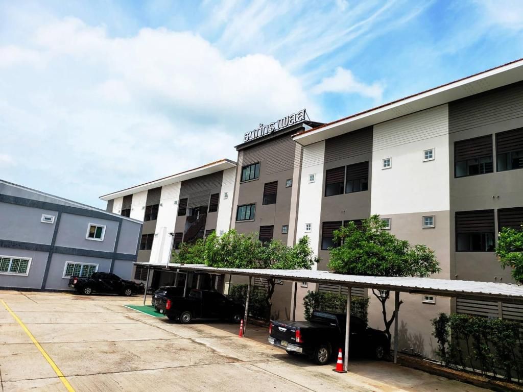 Un edificio de varios pisos con zona de estacionamiento techada y varios vehículos.