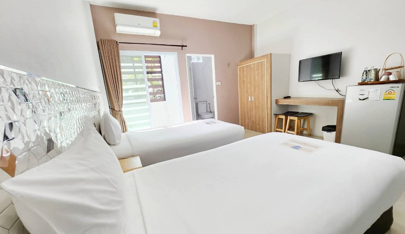 Habitación de hotel con dos camas, televisión, escritorio con silla y ventana con cortinas.