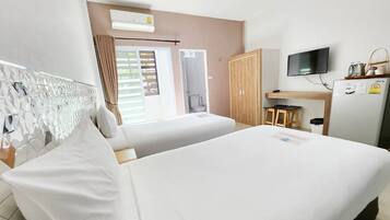 Habitación de hotel con dos camas, televisión, escritorio con silla y ventana con cortinas.