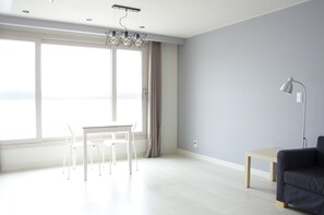 A modern living room with a dining area, large windows, and a view of the sea. - Terrace (Busan)