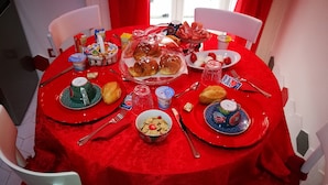 Una mesa redonda con mantel rojo, rodeada de sillas blancas.