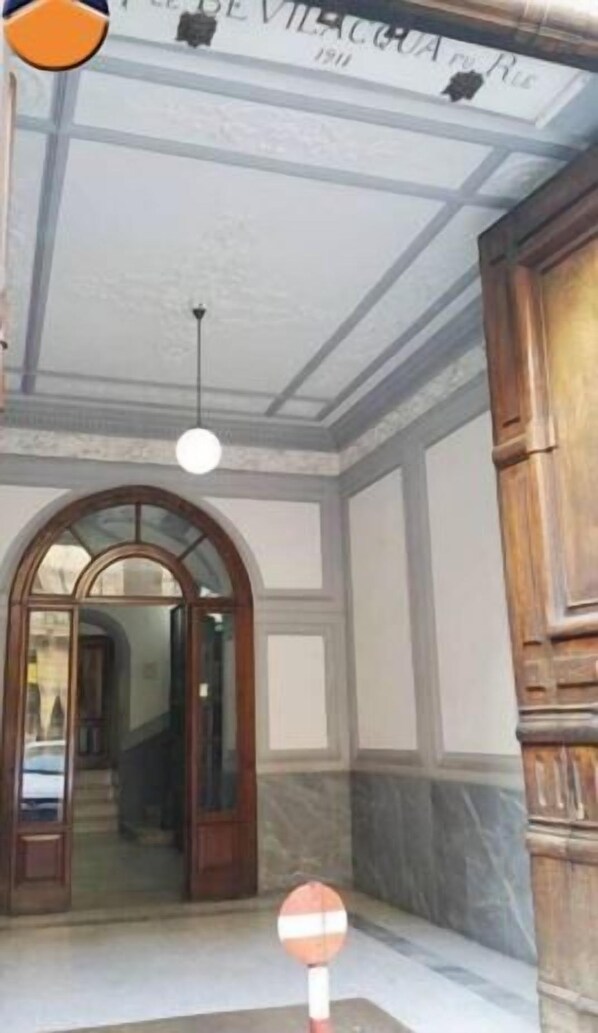 A hotel interior with a grand arched doorway, a chandelier, and a sign with the hotel's name. - B&B Resta cu mme (Naples)