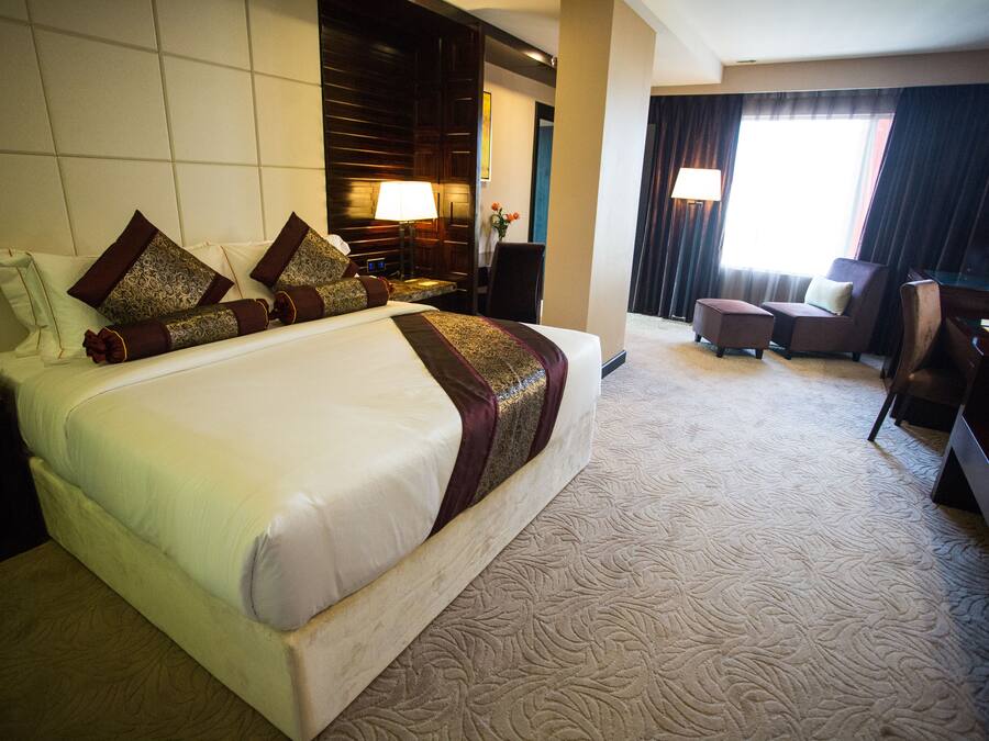 A hotel room with a large bed, a desk, and a chair.
