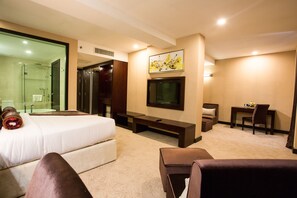 A hotel room with a bed, a TV, a desk, and a shower.