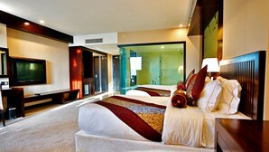 A hotel room with a large bed, a TV, a desk, and a glass wall. - Royale Signature Hotel (Alor Setar)