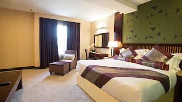A hotel room with a large bed, a desk, a chair, a mirror, and a window with curtains.