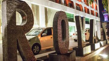 Large metallic letters spelling "ROYAL" on a sidewalk, with a building and parked cars in the background.