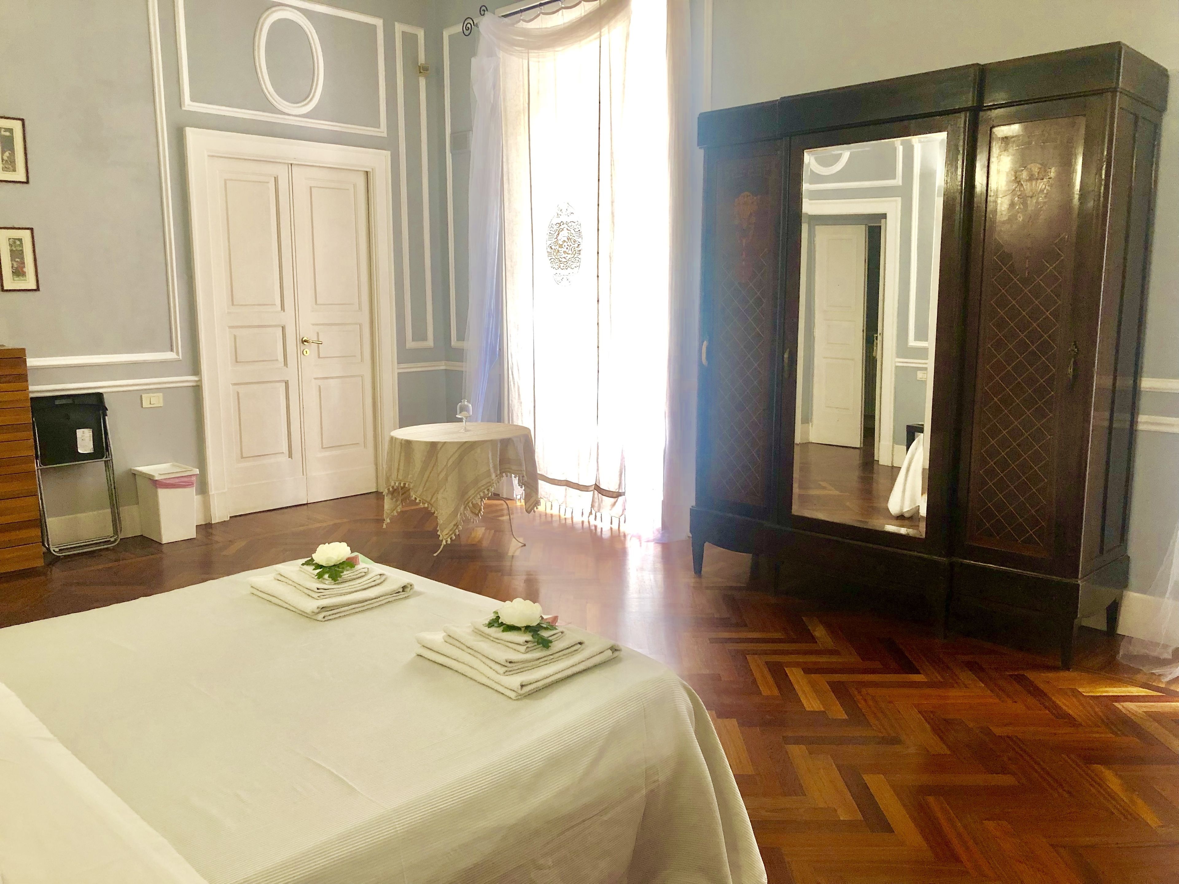 Una camera d'albergo con un letto, un tavolo rotondo, uno specchio e un armadio.